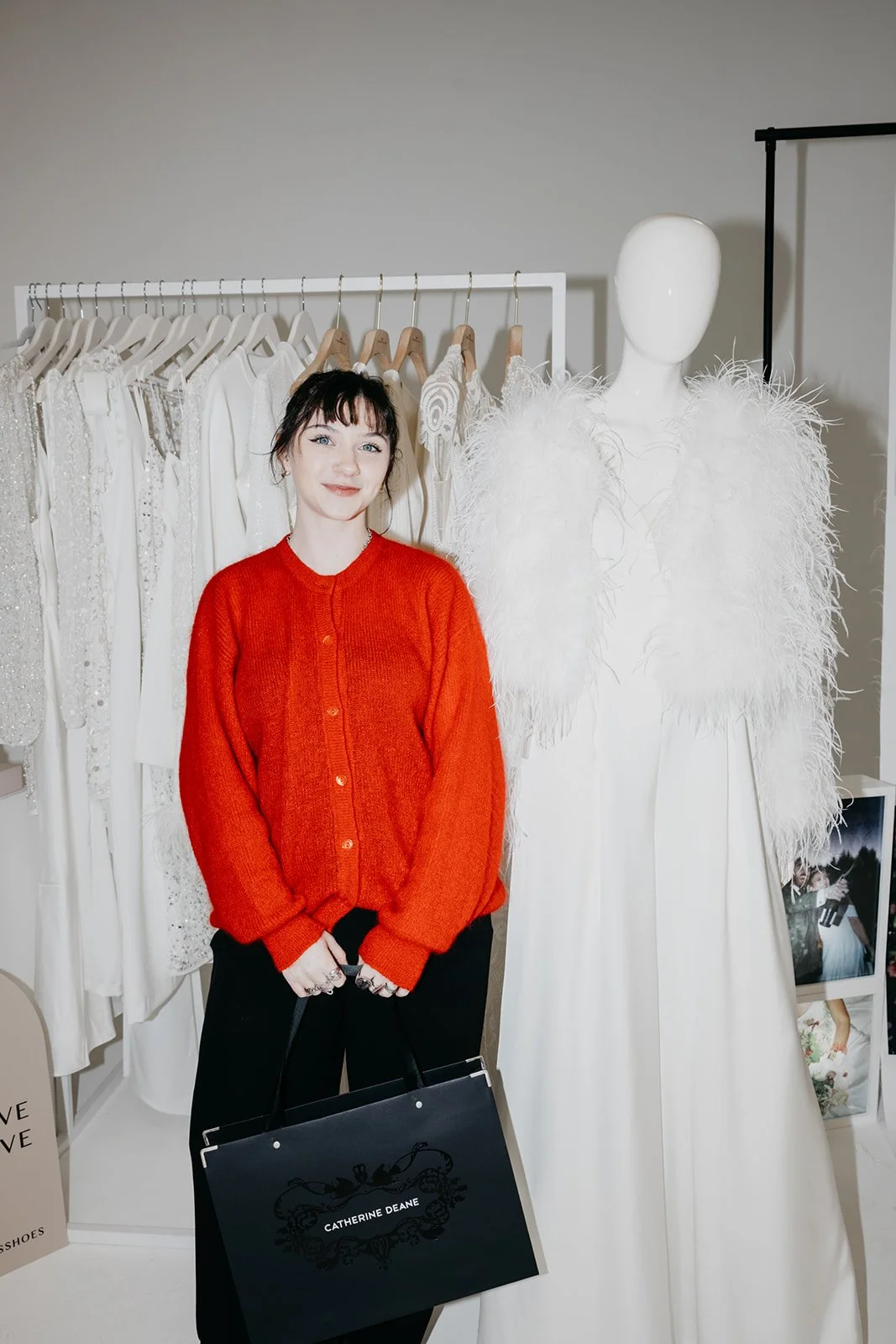 A woman in a red cardigan is standing next to a modern bridal display at a wedding fair.