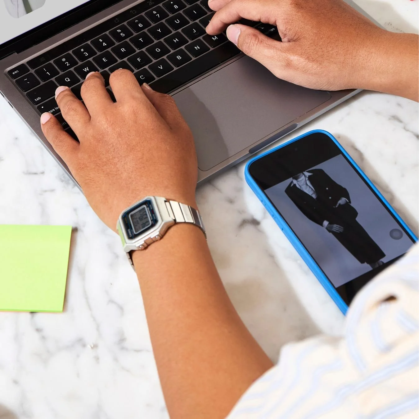 An image of someone looking at an advert for groomswear on their phone and then typing into a laptop.