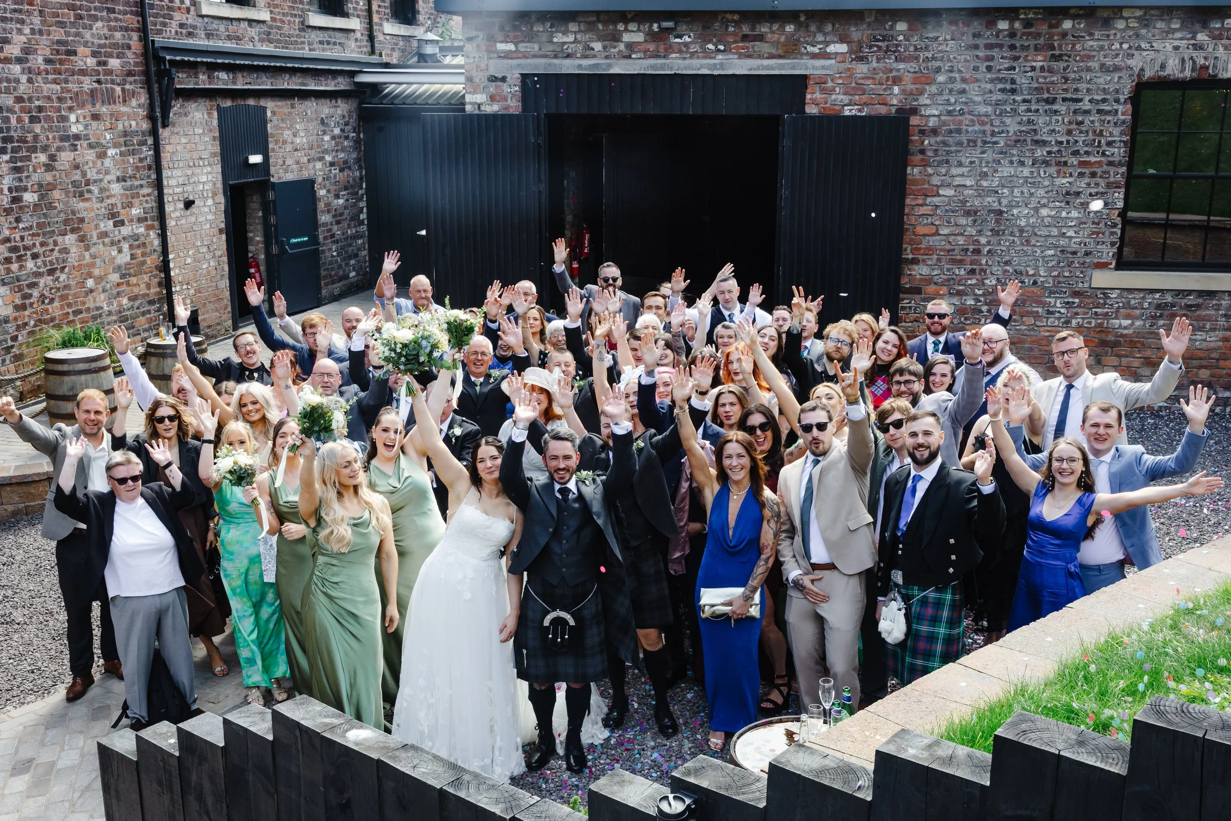All together now! Guests smile and wave at the Camera in the outdoor area behind The Engine Works.