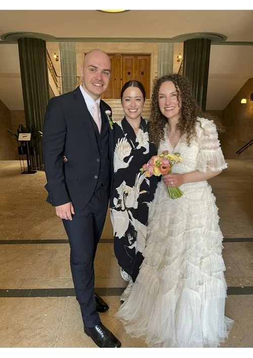Wedding celebrant Vicky standing with a newly married couple indoors, smiling together after a joyful ceremony.
