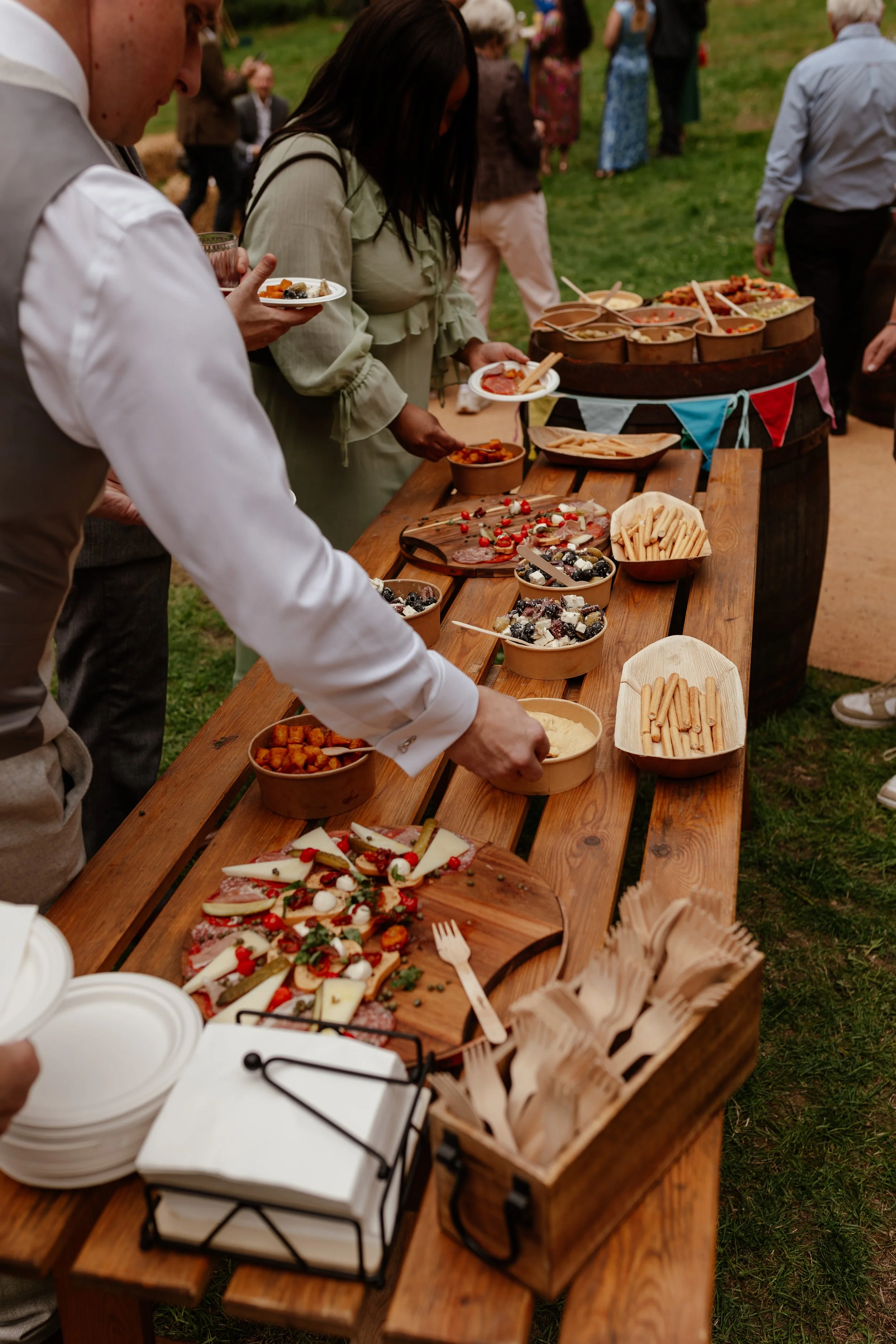 Wedding guests helping themselves to a rustic feast at an outdoor woodland wedding.