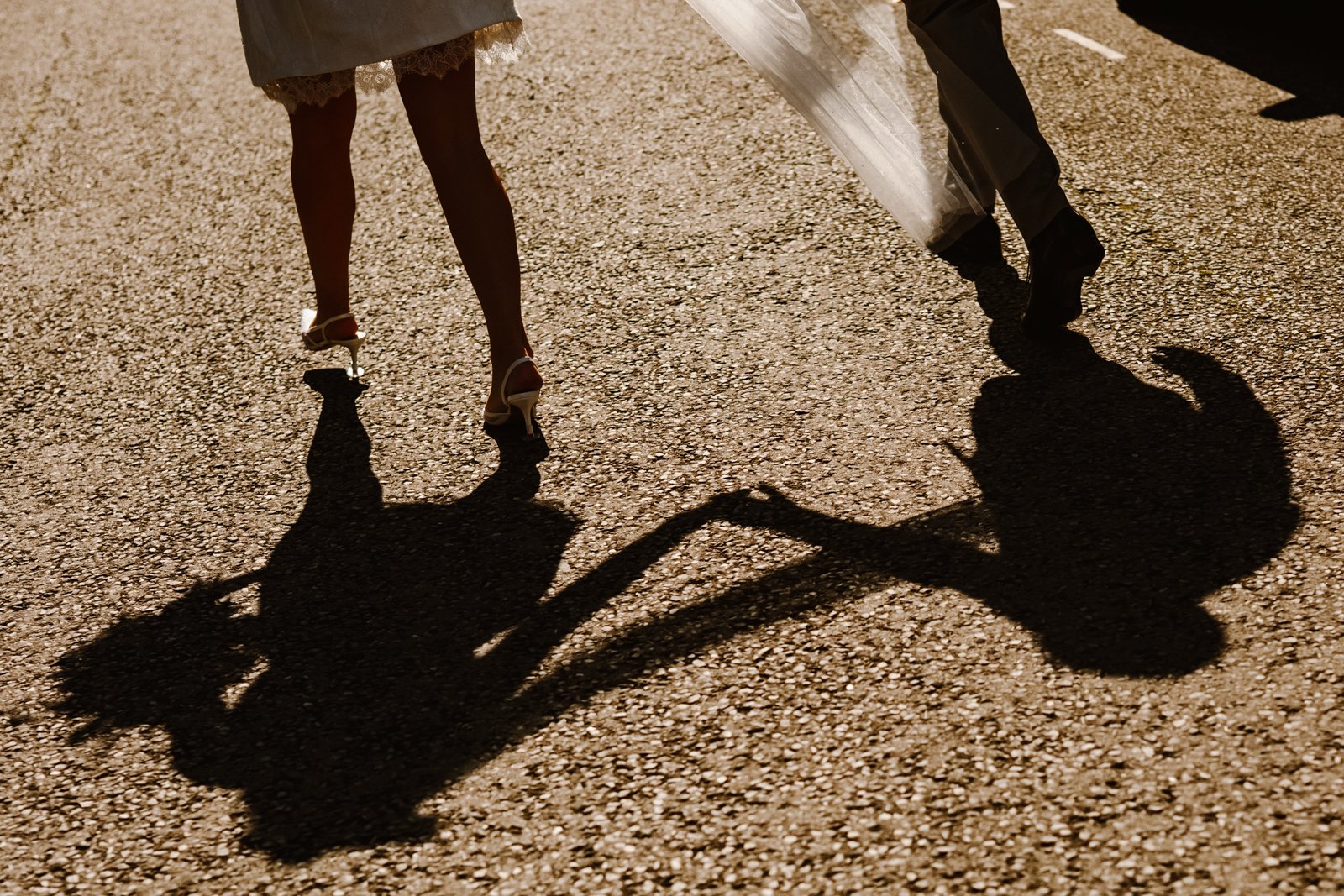 Romantic golden hour wedding photo in a countryside field, featuring a bride and groom kissing among a flock of sheep with a stunning sunset backdrop. A cinematic farm wedding portrait captured by Bluebell Photo Studio.
