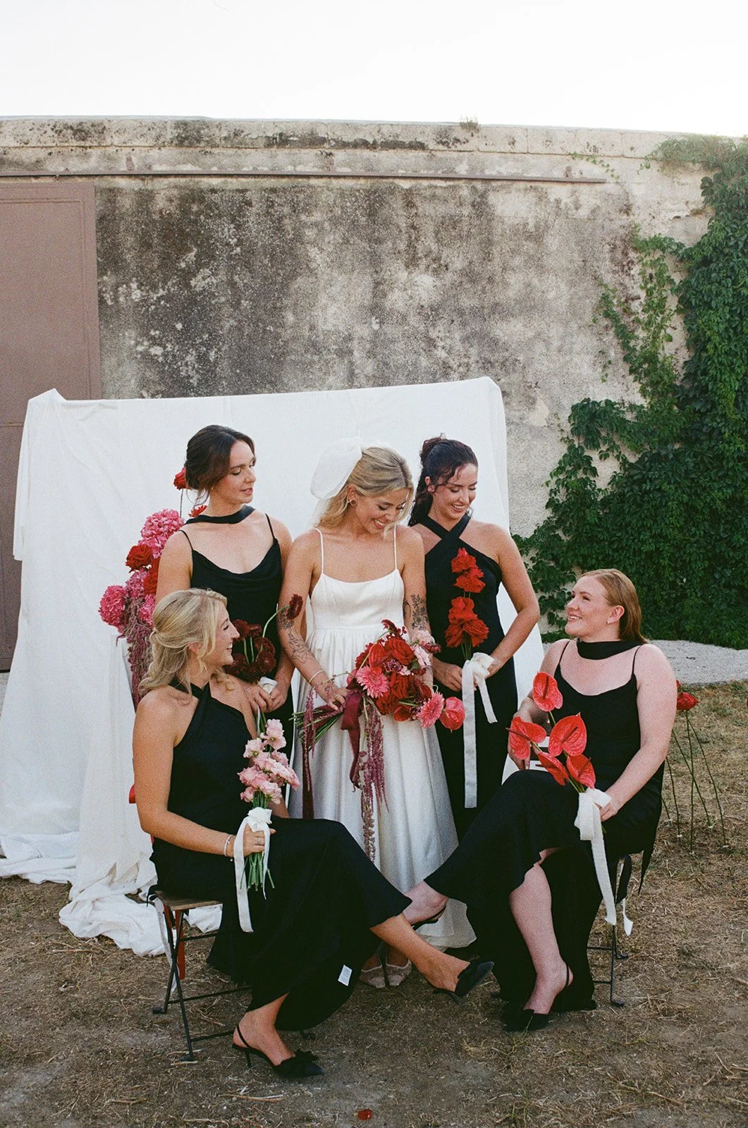 A beautifully styled bridal party exuding understated sophistication. The bride wears a silky ivory gown with delicate straps and a soft gathered skirt, while her bridesmaids complement her in black satin dresses by Rewritten Bridal Wear - each with 