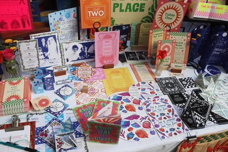 Vibrant wedding stationery display by Different Day Design Studio, Dorset. Showcasing a bold mix of colourful, creative designs - from celestial and botanical themes to retro and seaside styles - this collection highlights bespoke invitations, menus,