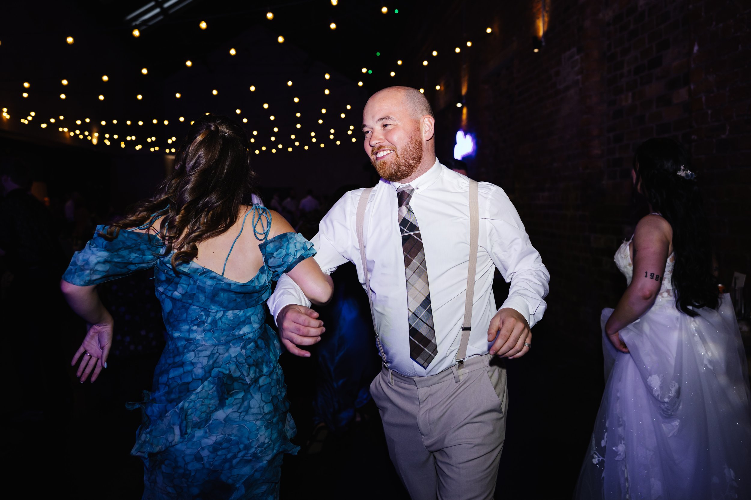 Smiling guests dancing arm in arm at The Engine Works, Glasgow.