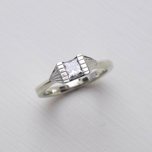 Modern silver engagement ring with a princess-cut diamond by Daniel Darby Jewellery Designer. Handcrafted in the UK, this sleek and geometric design offers a contemporary twist on classic bridal elegance.