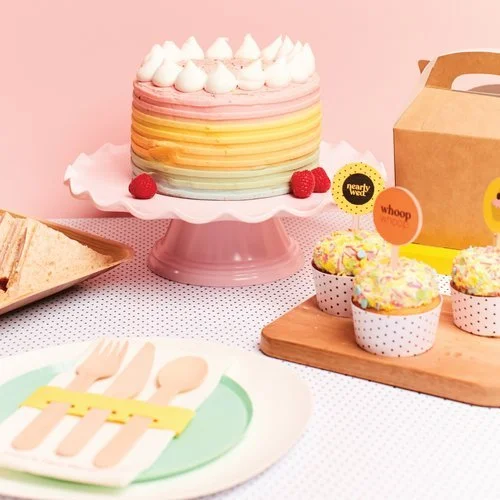 Personalised hen party tableware set with wooden cutlery wrapped in a yellow band on a mint green plate, featuring 'Lucy's Hen Party' text, designed by Melon Teaspoon.