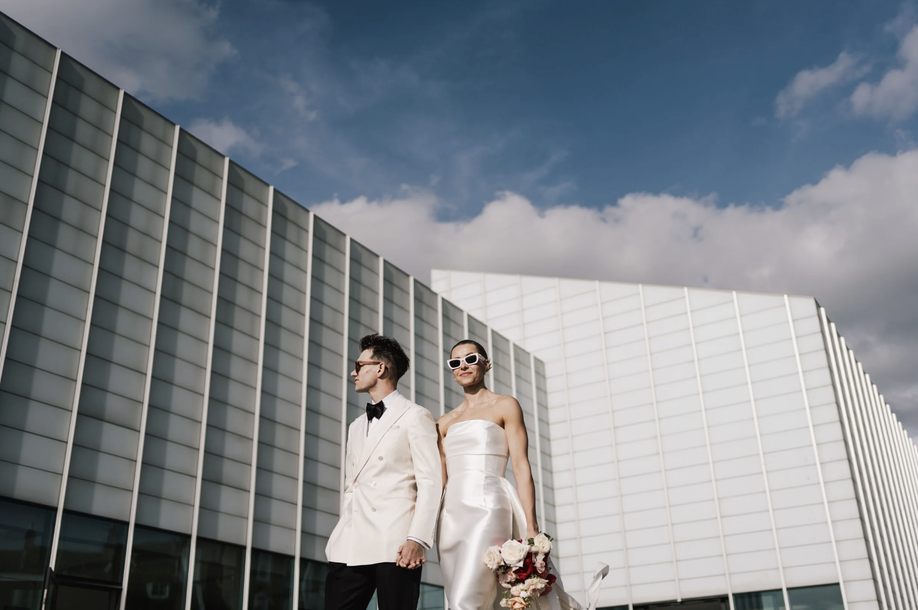 A stylish photo of a modern bride and groom walking outside The Tate Modern in Margate.