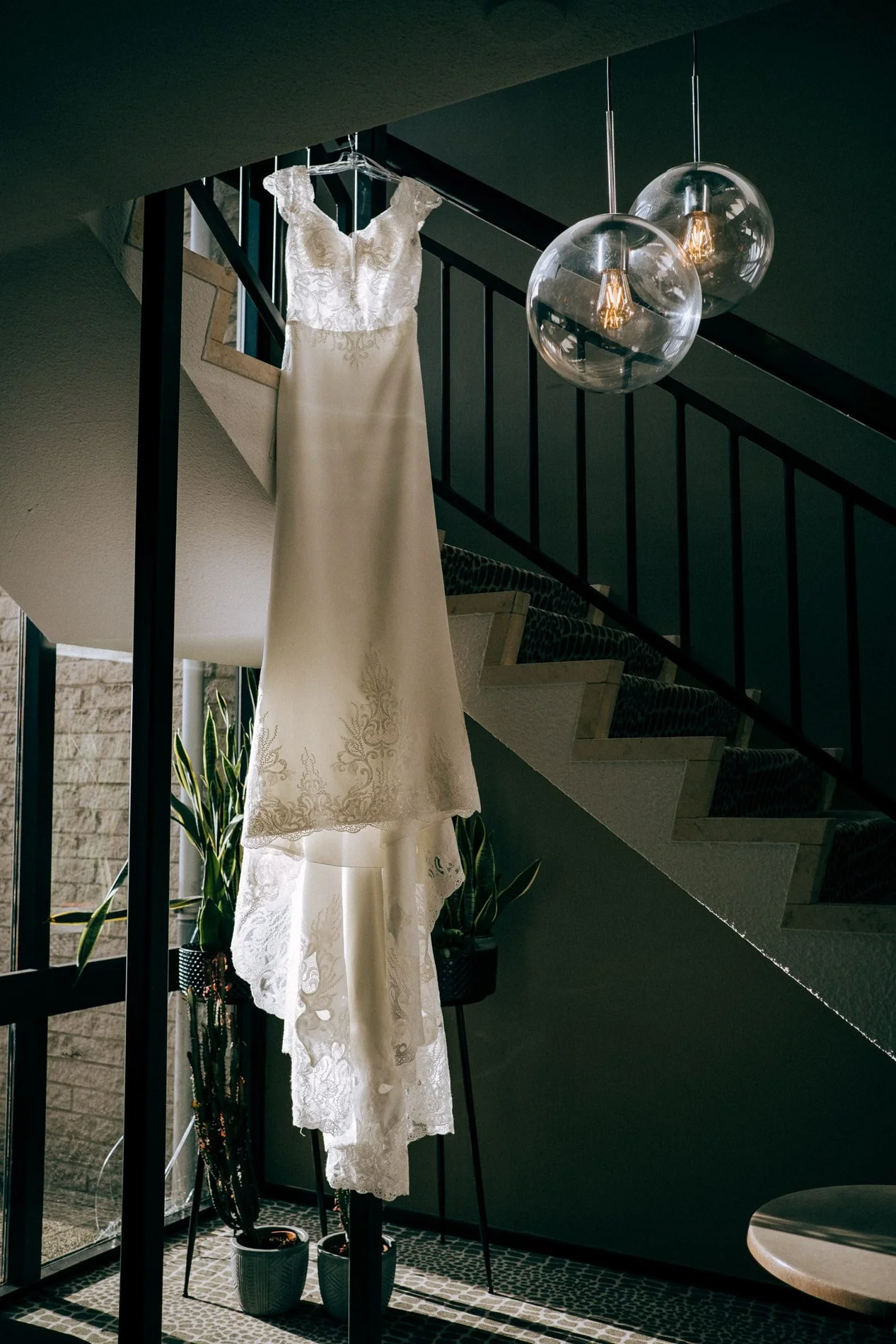 A lace wedding dress hangs gracefully in soft natural light during bridal preparations, captured in a calm, elegant style by Quiet Mornings Wedding Photography in Scotland.