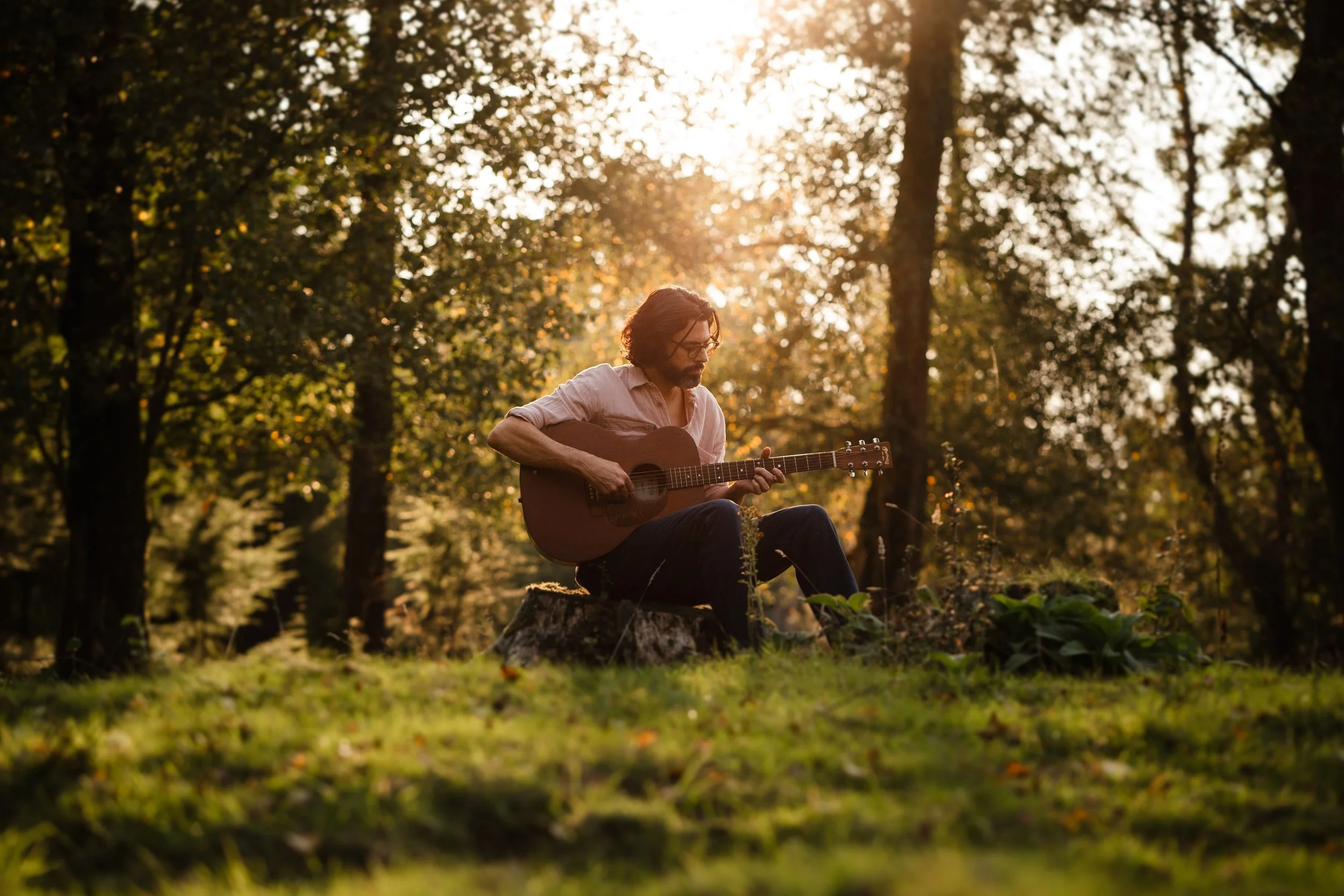 Thomas J Wilman, an acoustic wedding singer and guitarist, performs in a peaceful woodland surrounded by golden light. His warm, heartfelt style makes him ideal for outdoor ceremonies, rustic weddings and relaxed live music moments. Clarkie Photograp