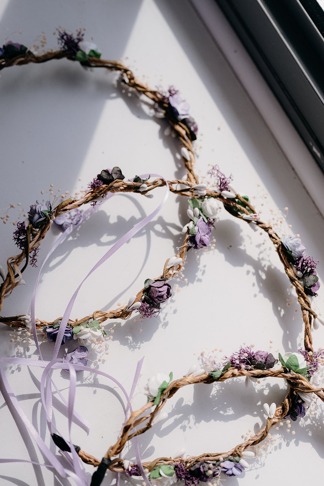 A close up of some pretty flower crowns with lilac flowers and ribbons.