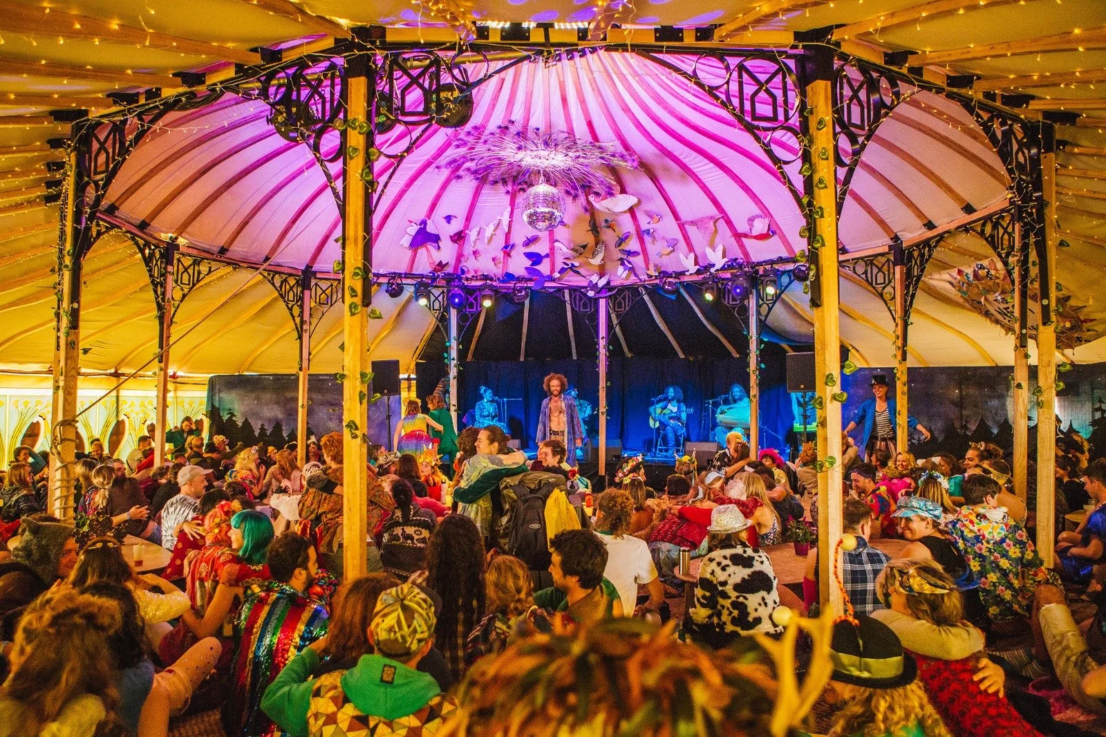 A festival-style wedding ceremony led by celebrant Lonan Jenkins, with guests gathered inside a vibrant marquee filled with colour, live music and dancing. This candid moment captures the energy, community and relaxed atmosphere of a modern, alternat