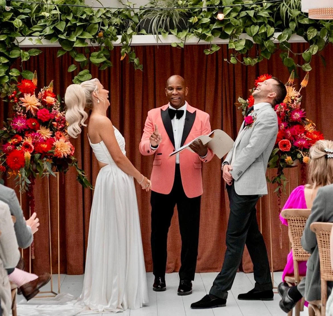Dave Octave Celebrant in a pink blazer, sharing a funny moment during a ceremony.