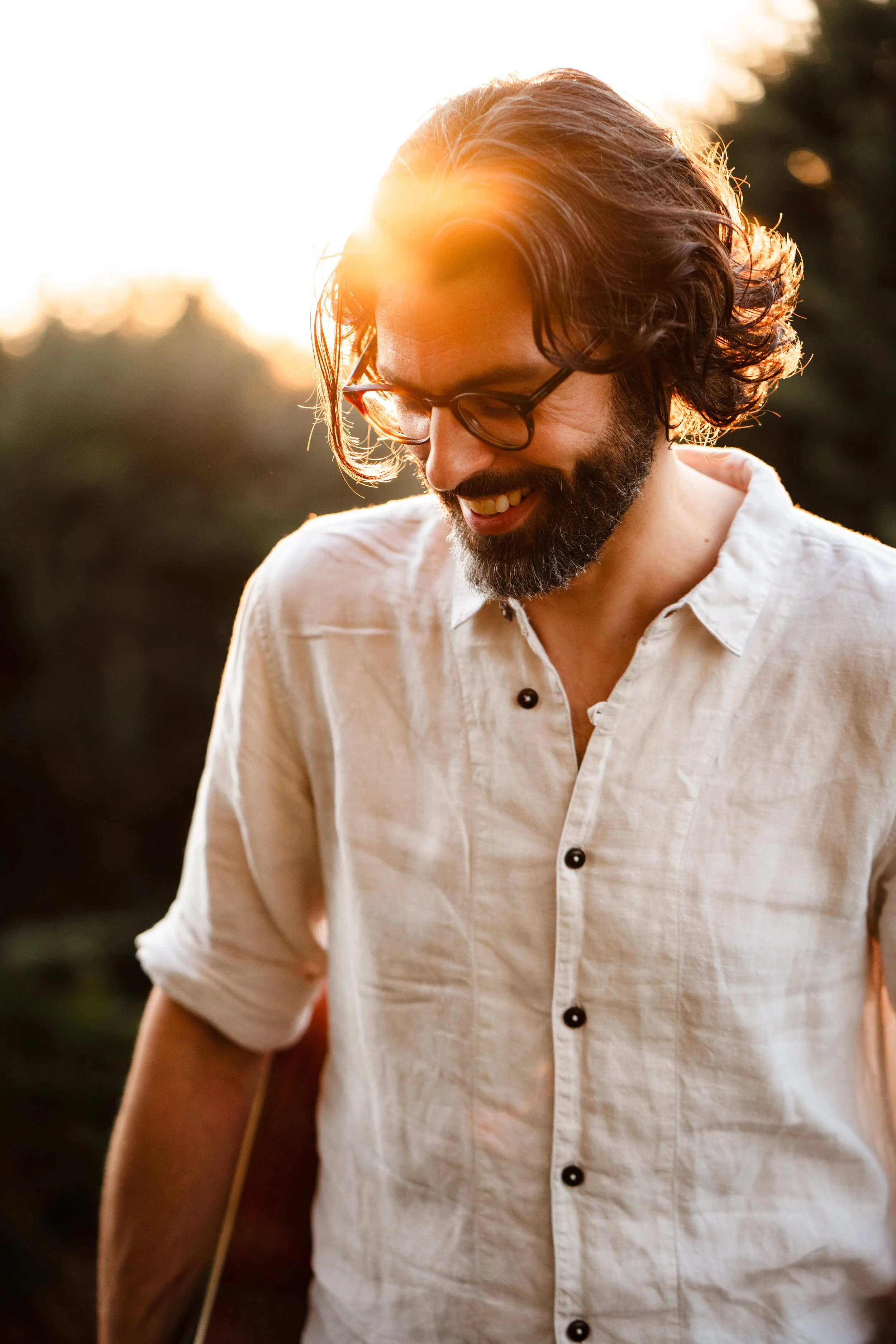 Thomas J Wilman, acoustic wedding singer and guitarist, smiles in the warm glow of sunset, creating a relaxed and natural atmosphere. His timeless style and heartfelt performances make him a perfect choice for romantic outdoor weddings and intimate a