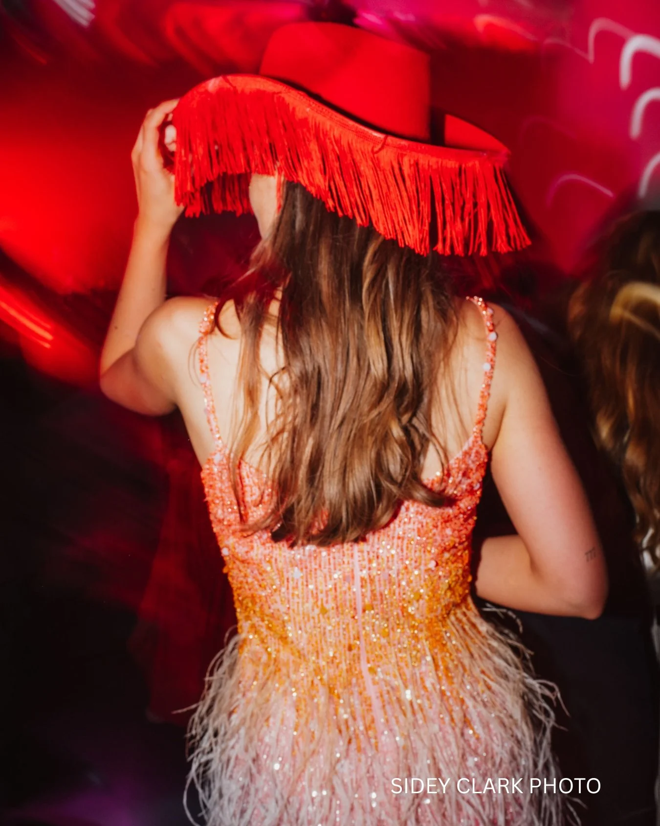 An alternative bride is wearing a sequin dress and a red cowboy hat.