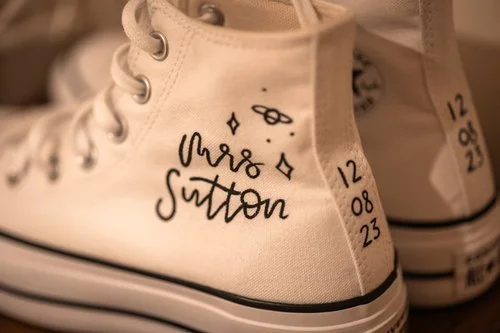 Personalised wedding trainers illustrated by Bee Davies Illustration. Featuring hand-painted calligraphy with the bride’s name and wedding date, these custom shoes add a fun, creative touch - perfect for modern brides looking for unique, wearable wed