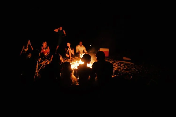 A beautiful wedding celebration experience, around a campfire on the beach, at night.