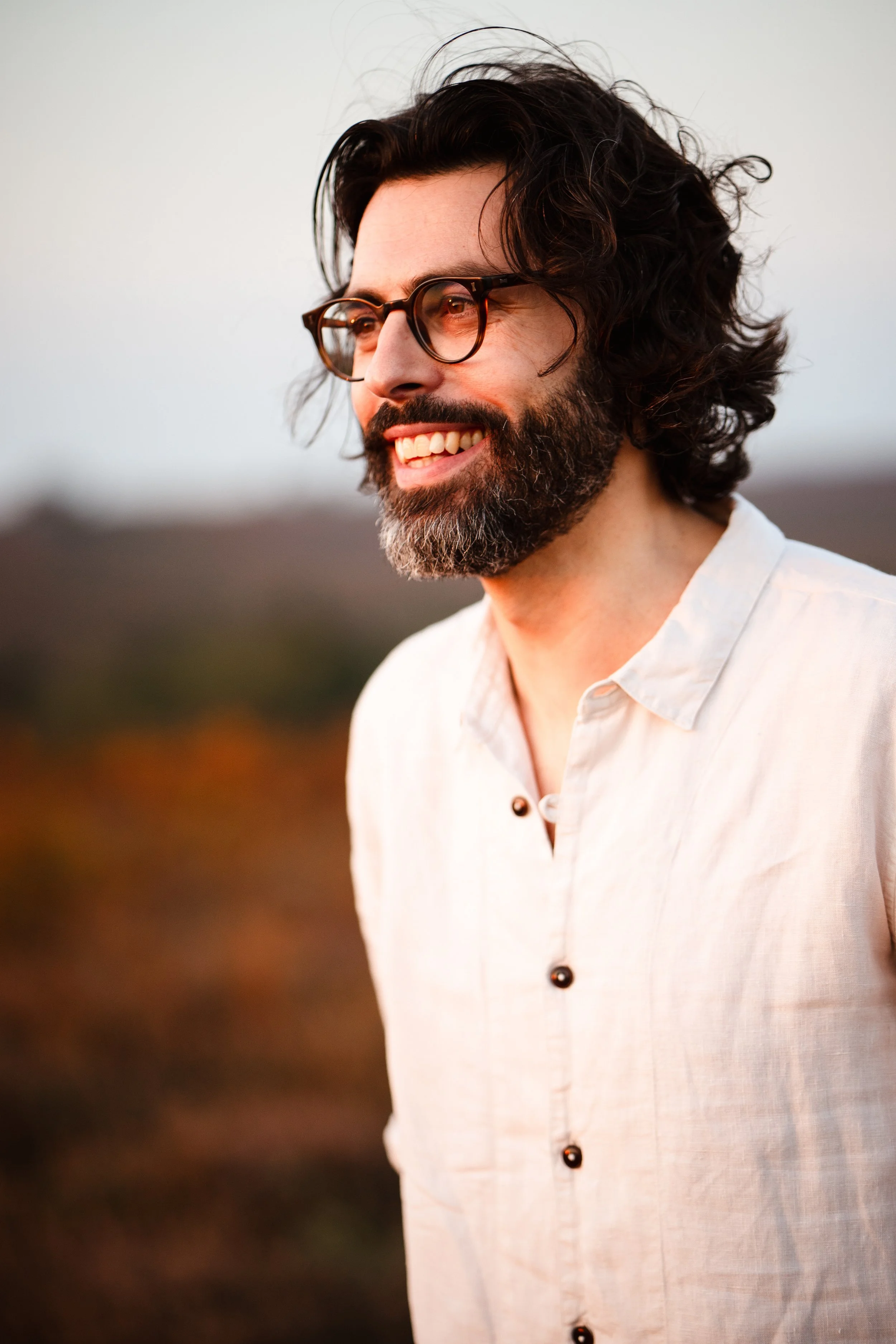 Thomas J Wilman smiles in the warm evening light, captured in a natural outdoor portrait. Known for his heartfelt performances, this acoustic wedding singer and guitarist brings authenticity and emotion to every wedding celebration. Clarkie Photograp