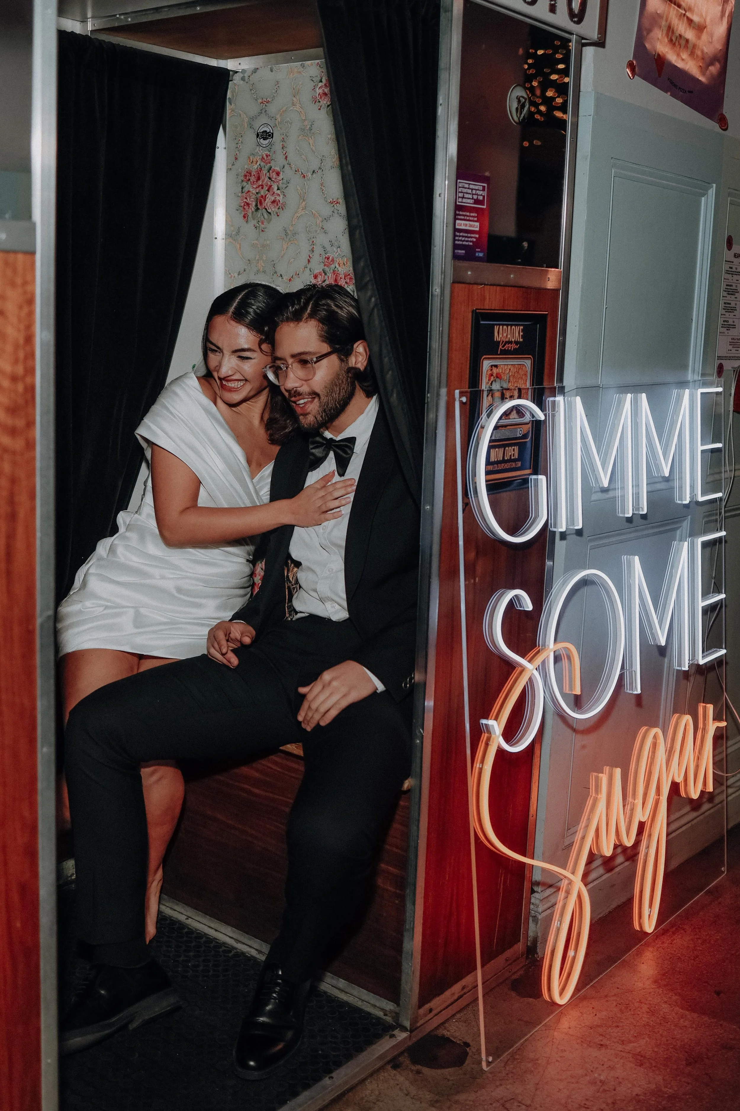 Bride and groom share a joyful moment inside a retro photo booth at Colours Wedding Venue in Shoreditch, capturing a playful, modern London wedding celebration.