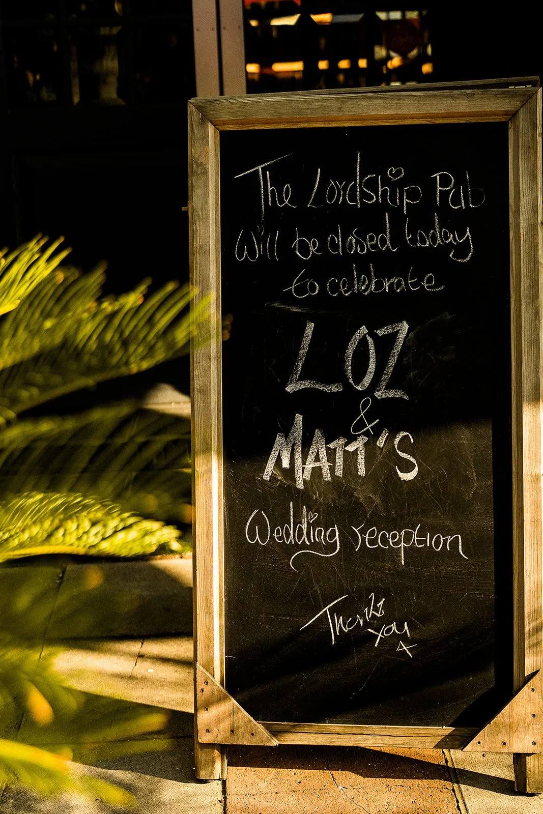 A chalboard sign that says 'we will be closed today to celebrate Loz and Matt's wedding reception'