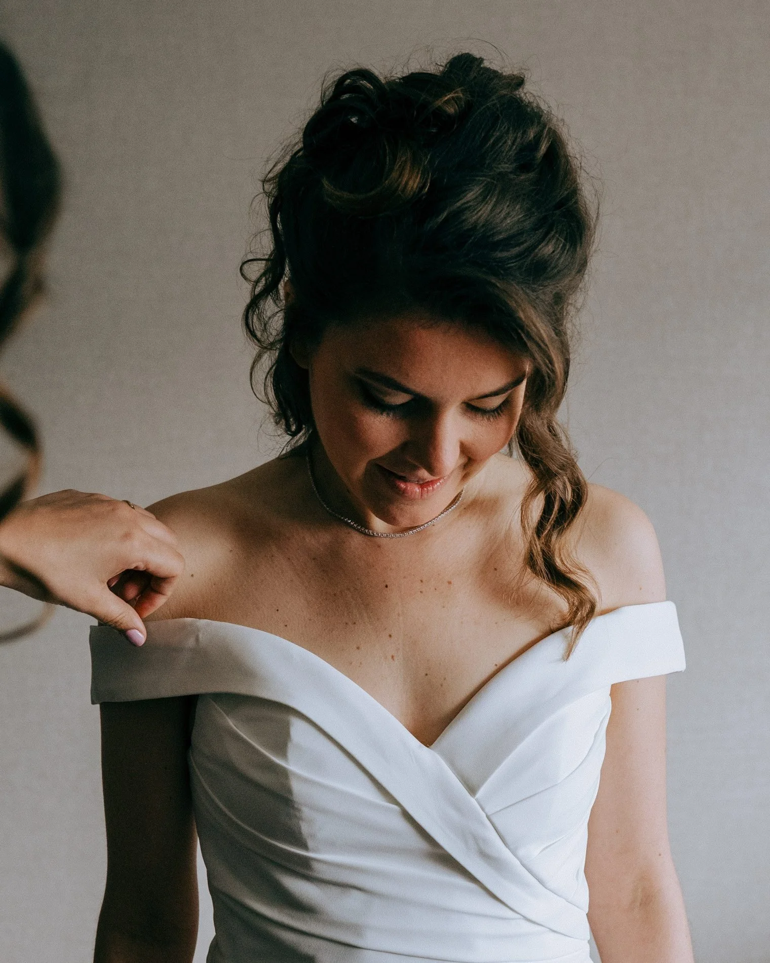 A quiet bridal preparation moment as the bride adjusts her dress, captured with soft light and natural elegance by Quiet Mornings Wedding Photography in Scotland.