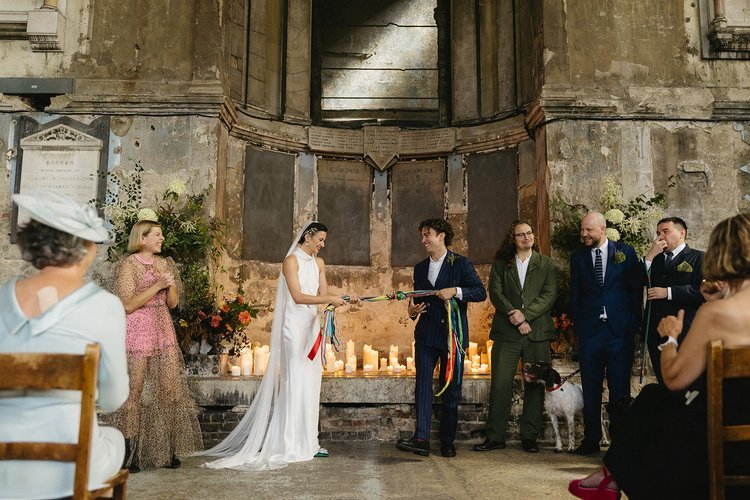 A couple celebrates their love in a candlelit ceremony led by modern wedding celebrant Tab Taylor in a historic UK venue. The pair take part in a colourful hand-fasting ritual, symbolising their unity and connection. Surrounded by family and friends,