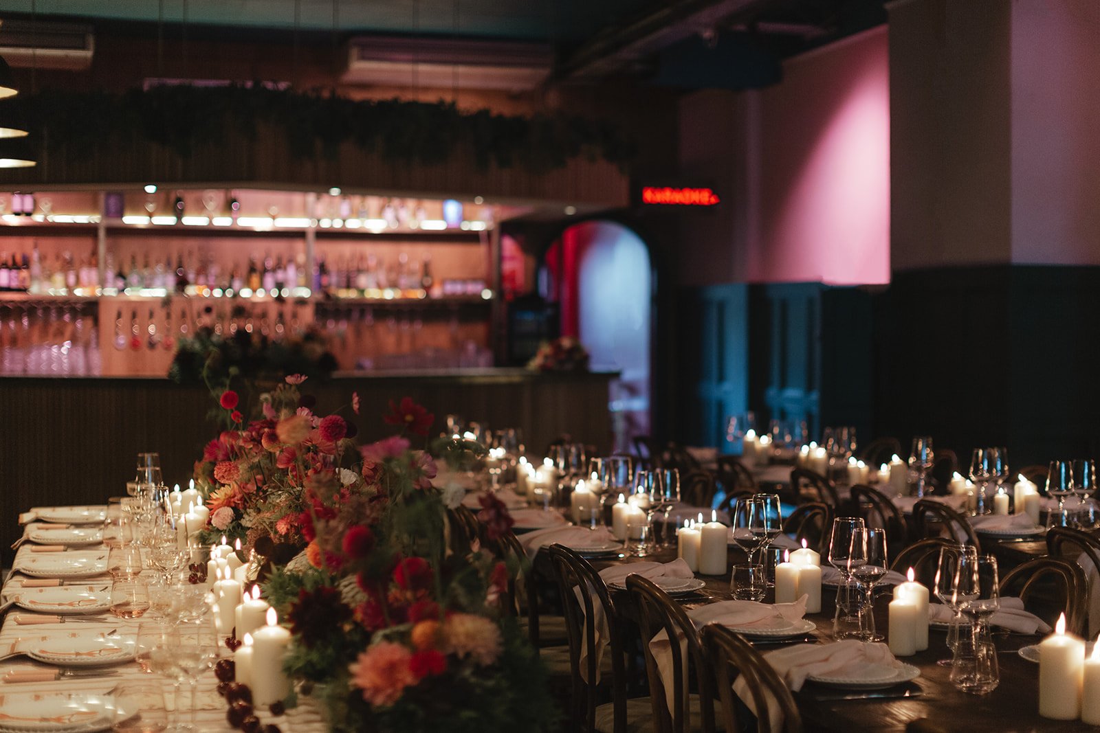 Candlelit banquet tables styled with florals inside Colours Wedding Venue in Shoreditch, capturing an atmospheric, modern London wedding reception setting.