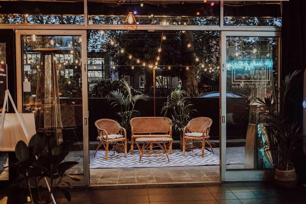 Stylish lounge seating framed by festoon lights inside Colours Wedding Venue in Shoreditch, showcasing a relaxed, modern London wedding space with indoor-outdoor flow.