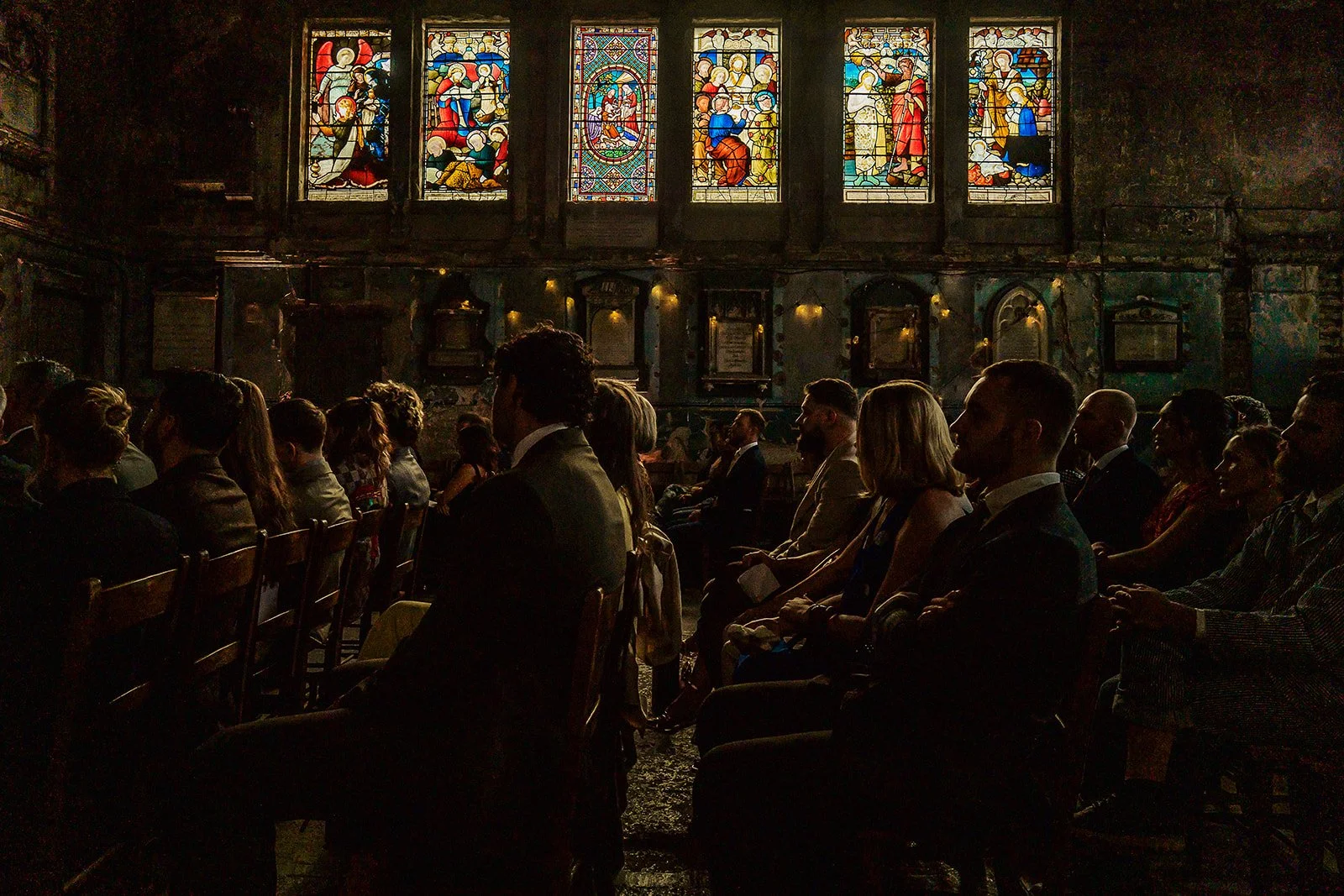 A beautiful image of wedding guests inside the Asylum Chapel with its stained glass windows.