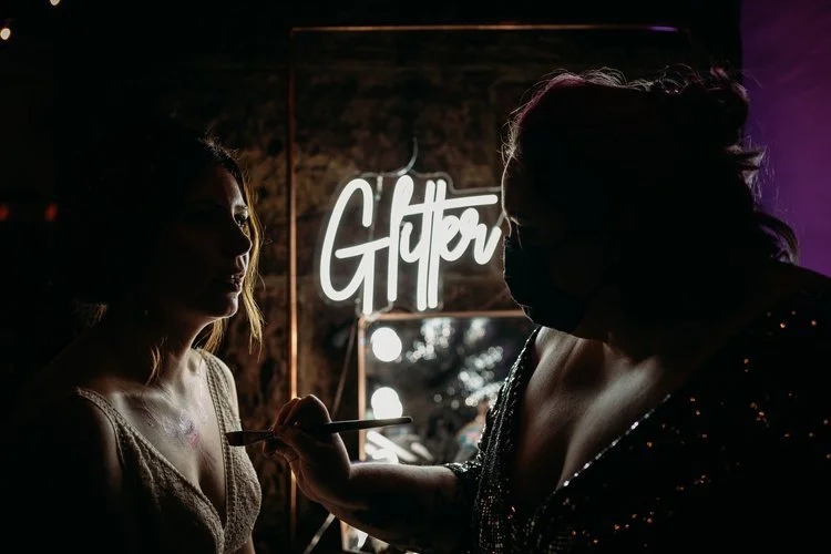 Give Good Face glitter bar artist applying sparkling face and body art to a wedding guest, creating a fun and glamorous experience for celebrations.