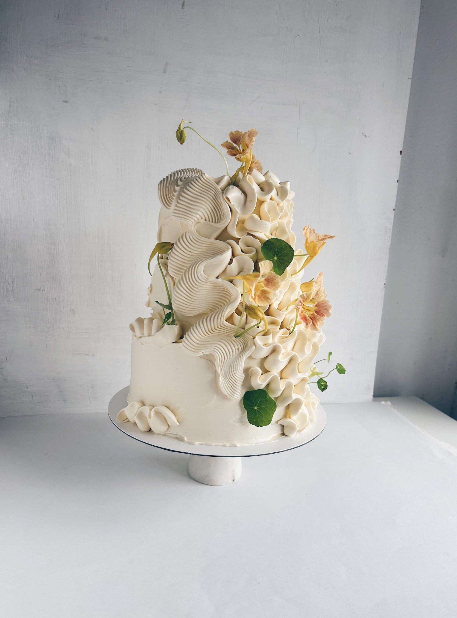 A beautiful wedding cake by Leeds based cake artist, Sarah and Cake. It's 2 tier with swirly, cream icing and yellow flowers.