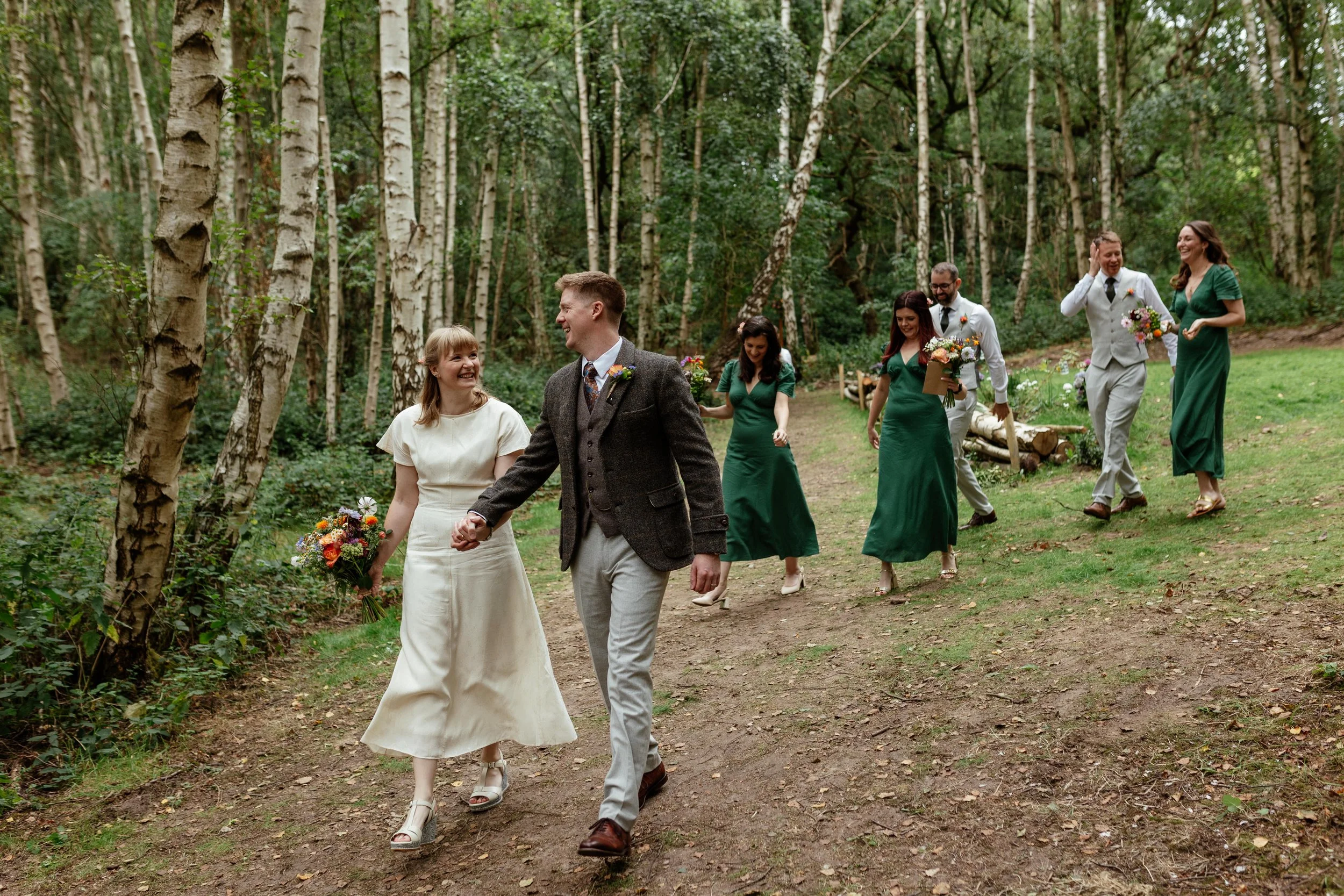 A bride and groom walking through Sherwood Glade with their bridesmaids and groomsmen.