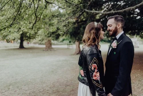 Romantic outdoor wedding portrait featuring a bespoke hand-painted leather jacket by Bee Davies Illustration. Adorned with floral artwork and personalised details, this creative piece adds individuality and style - perfect for brides seeking unique, 
