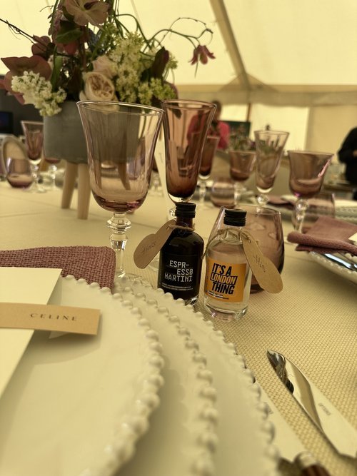 Mini bottles of Rythmik Cocktails’ Espresso Martini and It’s a London Thing are placed on an elegantly set wedding table, complete with mauve glassware, fresh flowers, and personalised place settings. These ready-to-drink cocktails add a stylish and 