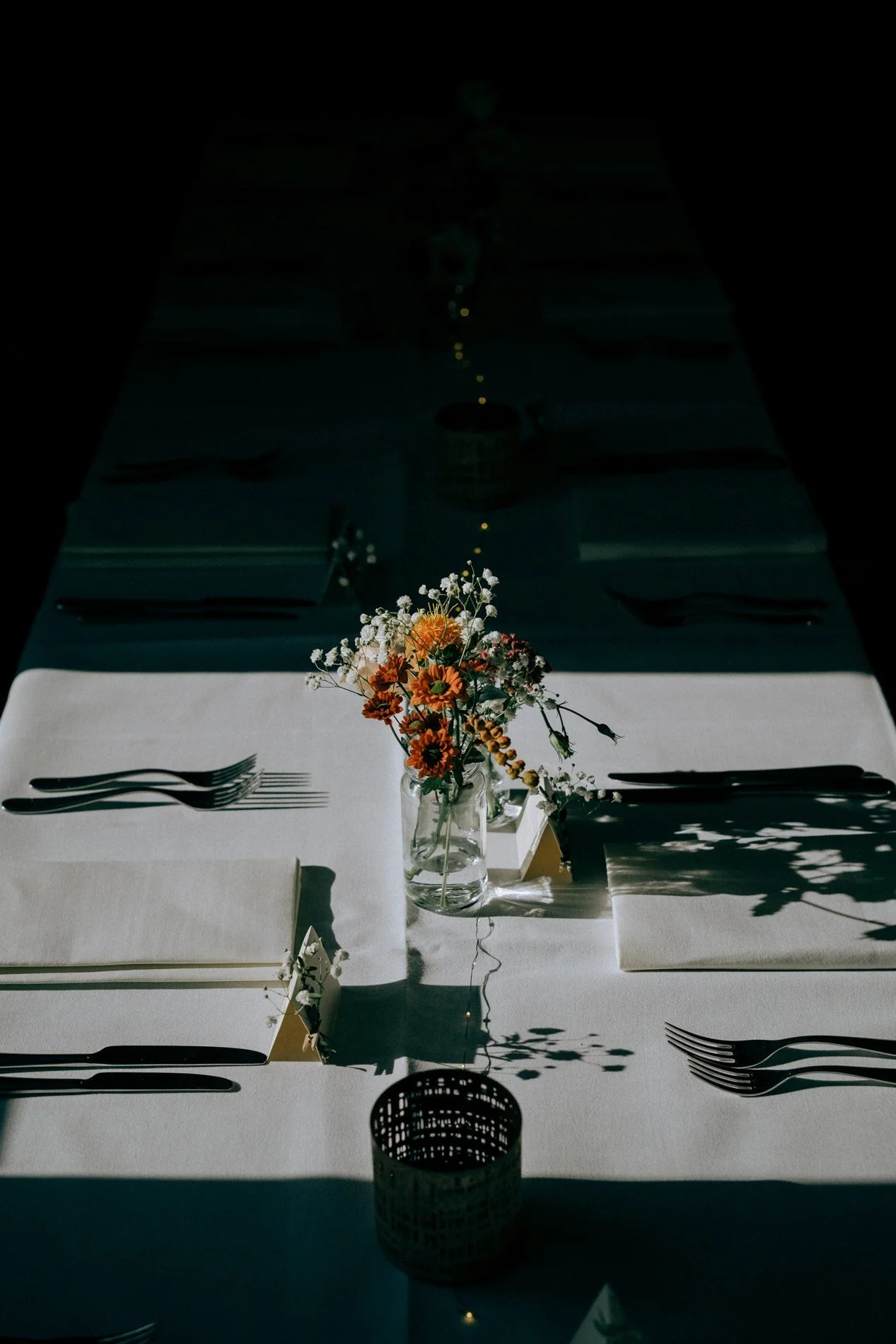 Minimal wedding table styling with flowers and dramatic light and shadow, capturing modern reception details by Quiet Mornings Wedding Photography in Scotland.