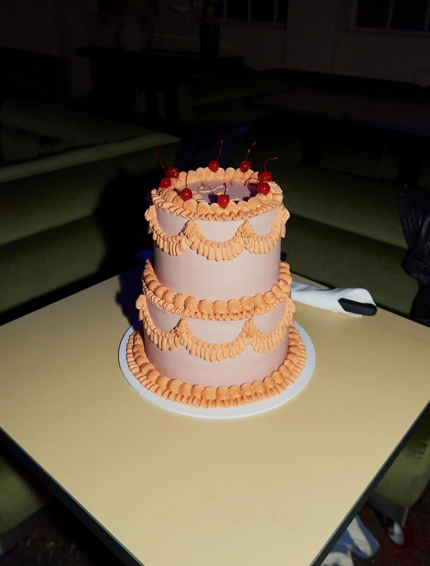 A pink and orange wedding cake by The Cake Hun. There are red cherries on the top.