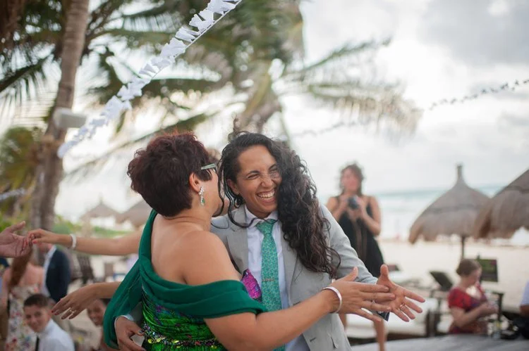 2 women dancing at a tropical beach wedding.