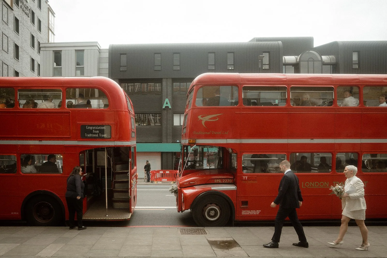 Joe and Rose stand by 2 London buses.