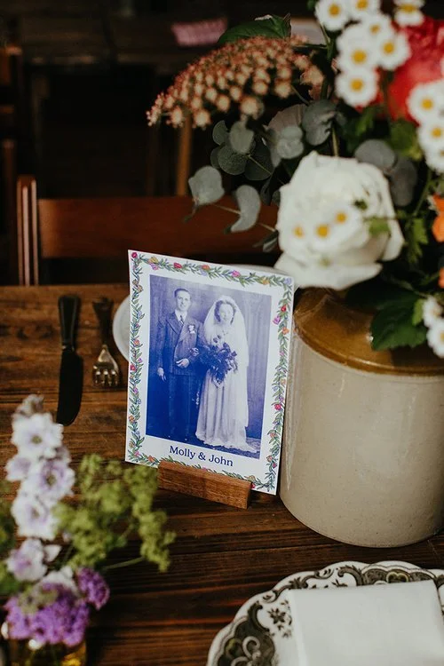 Vintage-inspired wedding table décor featuring a personalised photo display by Different Day Design Studio, Dorset. Surrounded by rustic florals and antique-style crockery, this thoughtful table design celebrates family heritage - perfect for meaning