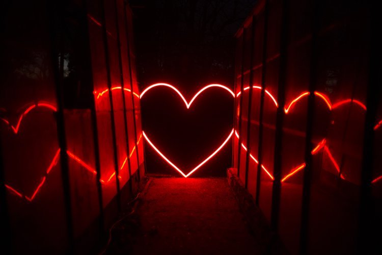 My Colour is Gold glowing red neon heart installation with mirrored reflections, creating a bold and romantic walkway feature for weddings and events.