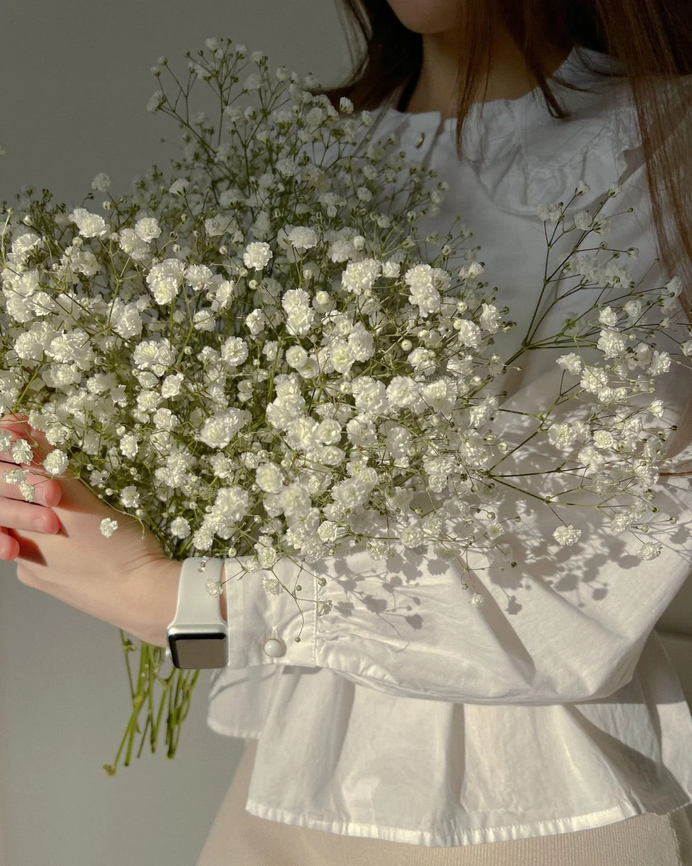 A wedding florist holding a bouquet of baby's breath.