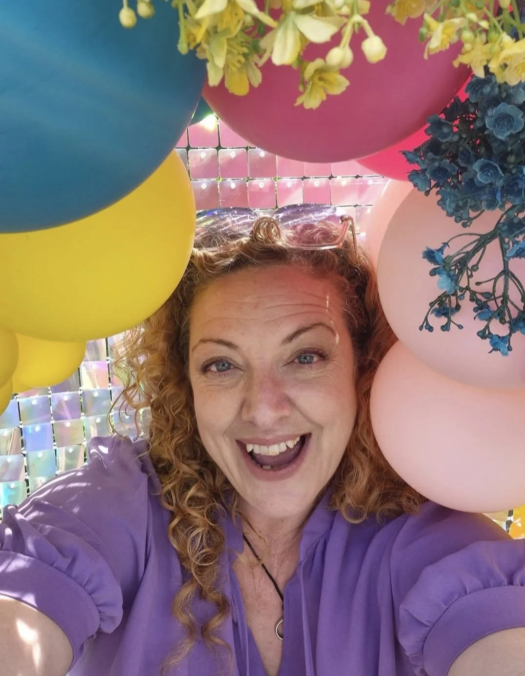 Melly The Celebrant smiling with some coloured balloons. 