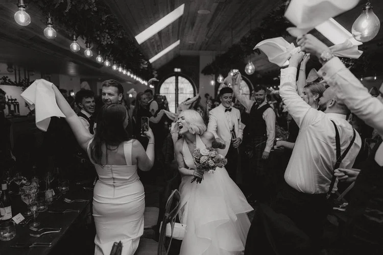 A burst of pure celebration, captured with F.D Young Photography’s signature energy. The room is alive - napkins twirling, guests cheering, and the couple right at the center of it all, laughing and swept up in the joy of the moment. It’s a frame fil