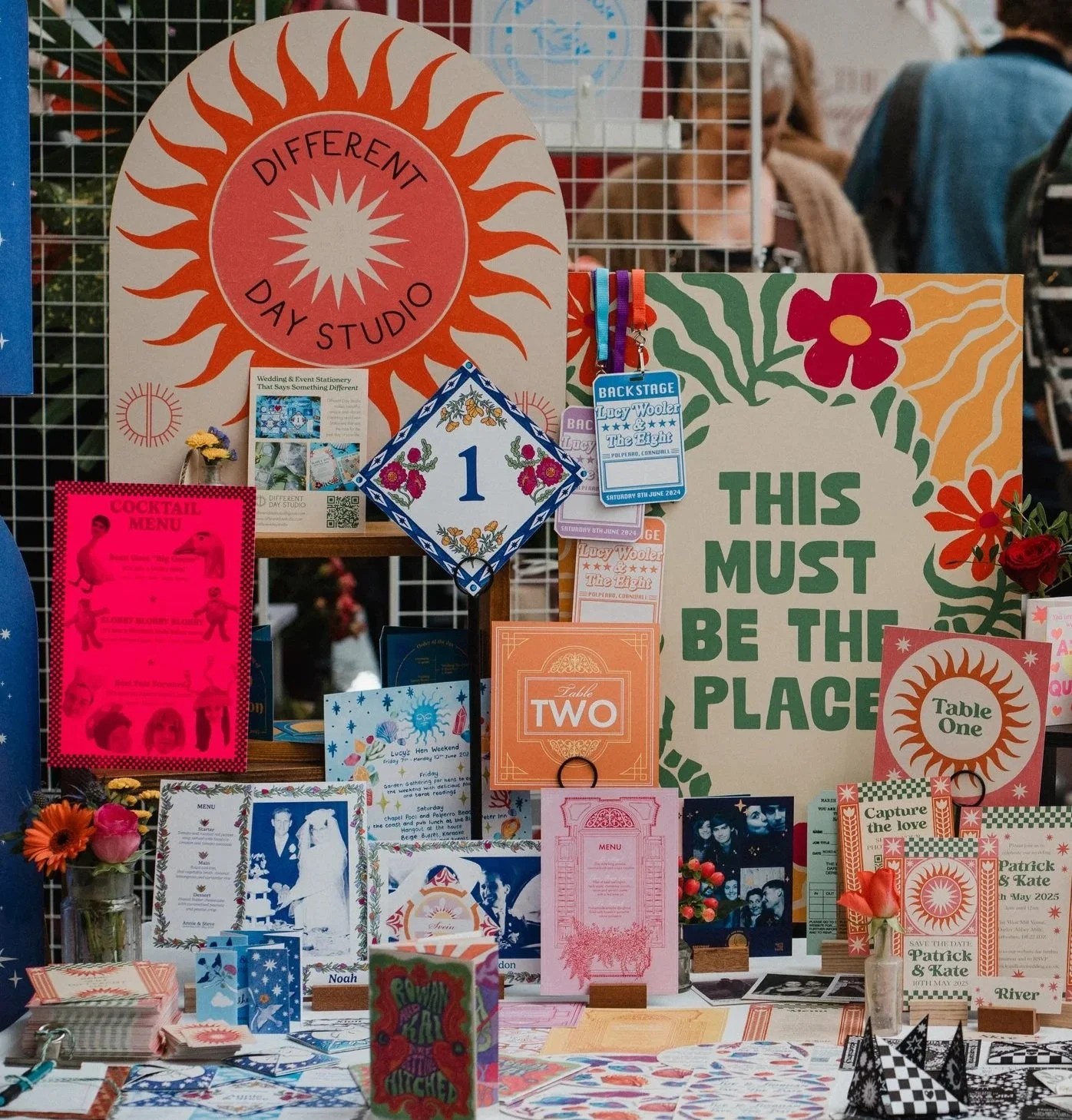 Colourful wedding stationery disply at a wedding fair. There is a big sign that says 'THIS MUST BE THE PLACE'