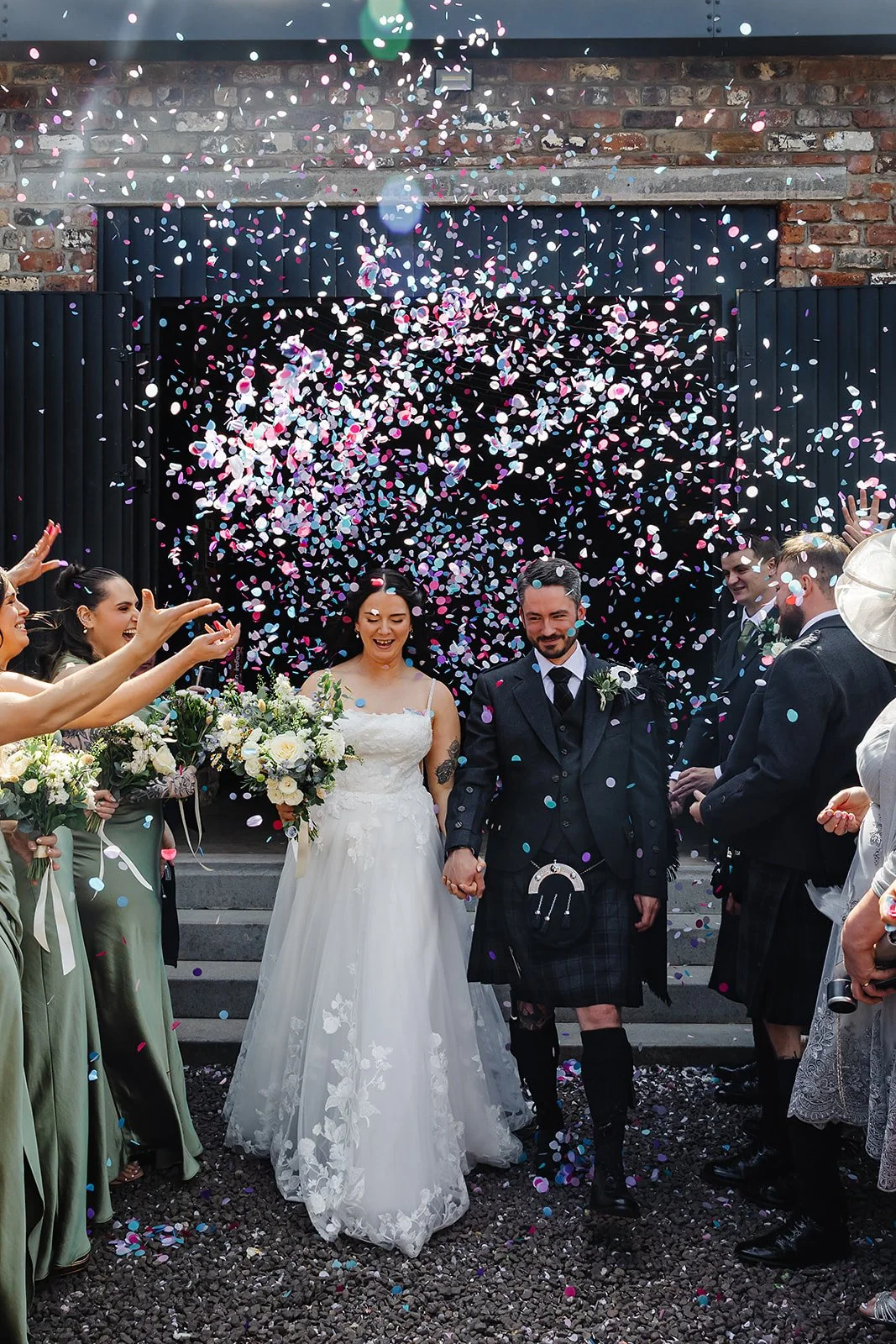 Marie & Oliver leave The Engine Works and walk into a confetti moment, thrown by their guests.