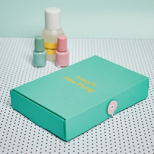 Custom turquoise gift box with yellow 'Lucy's Hen Party' text, designed by Melon Teaspoon for bespoke celebration packaging, styled with pastel nail polish bottles in the background.
