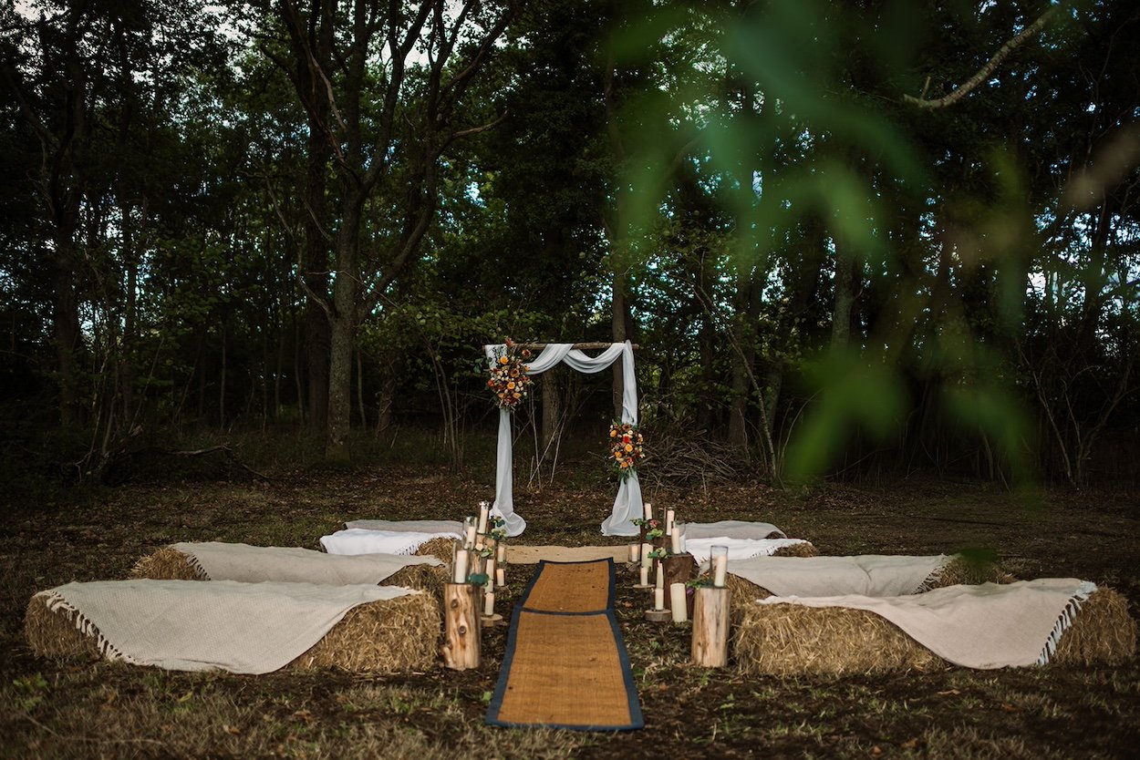 A woodland wedding ceremony setup with natural décor and rustic seating, creating an intimate, eco-friendly celebration planned by Wild Soul Weddings, eco wedding planners in the UK. Rach Elizabeth Photography.