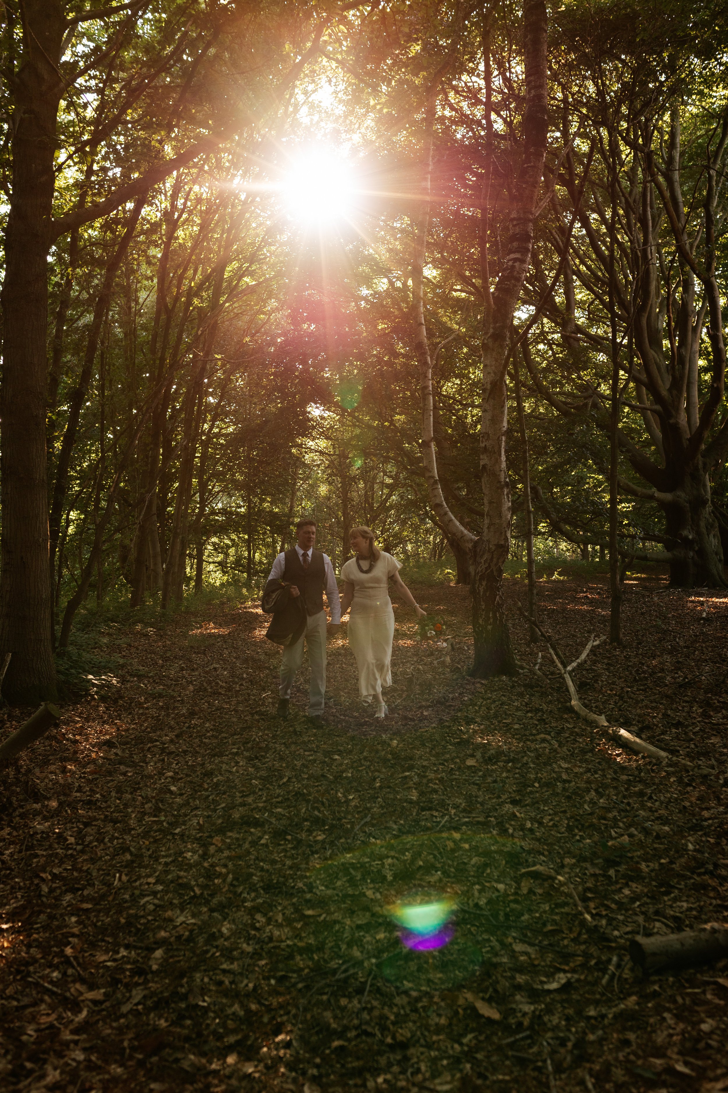 A bride and groom walking through Sherwood Glade at golden hour.