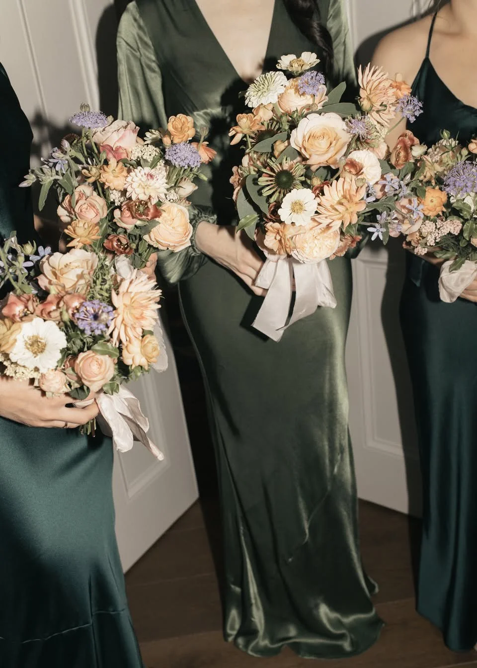 Elegant bridesmaid looks by Rewritten Bridal Wear, showcasing their signature deep green satin gowns. The dresses vary in style - from sleek cowl necks to long-sleeved silhouettes - reflecting Rewritten’s commitment to mix-and-match versatility that 