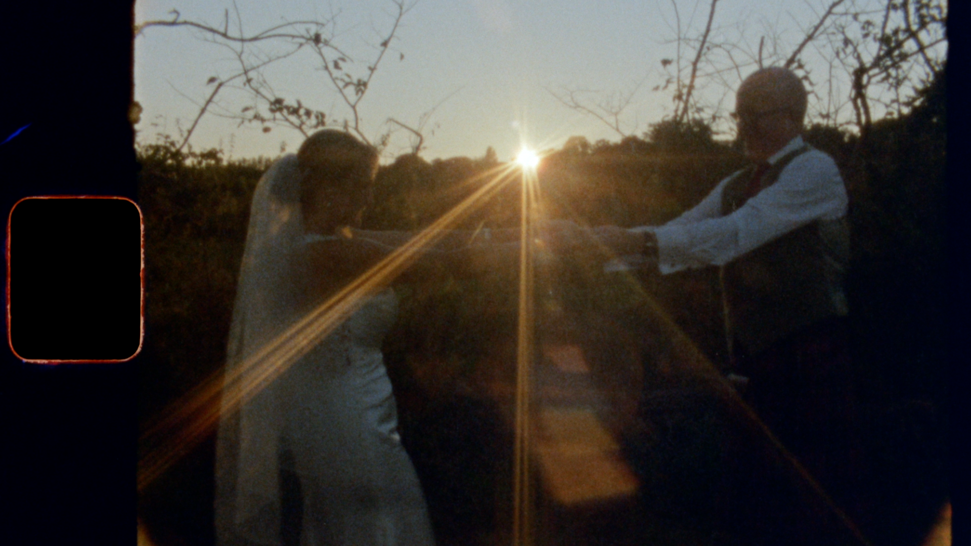 A dreamlike still of a bride and groom dancing in the golden hour on their wedding day. The still is nostalgic as it has been captured on Super 8 film.